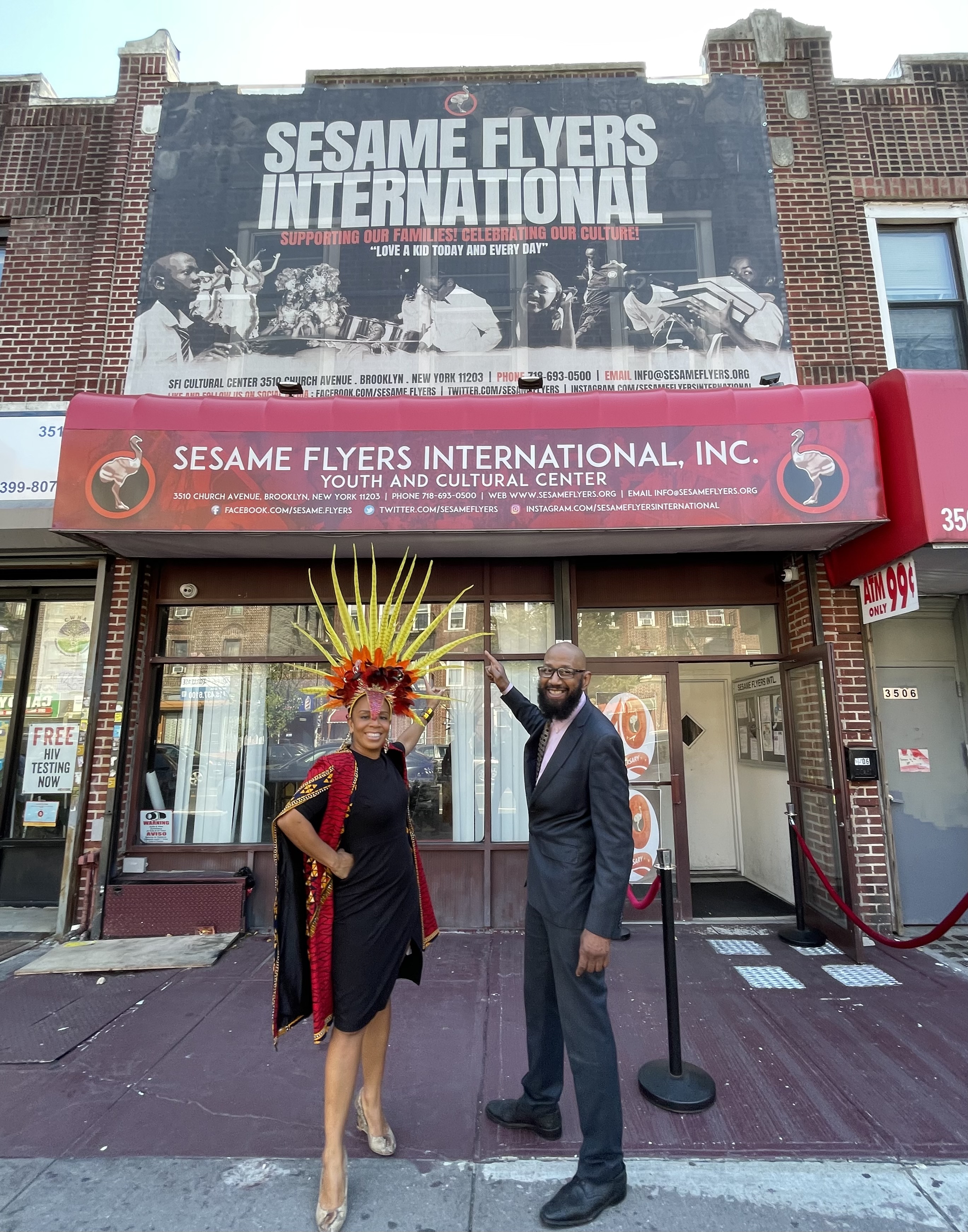 Commissioner Cumbo and Curtis Nelson point at the Sesame Flyers building sign.